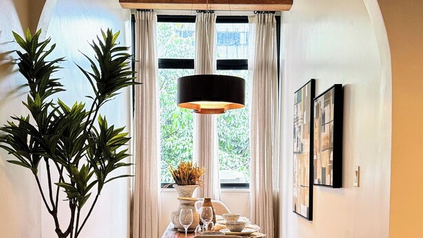 A dining area with a wooden table, chairs, a large vase, and a hanging light fixture. - Ipanema Premium Design · Renovated · Steps to Beach & Subway (Rio de Janeiro)