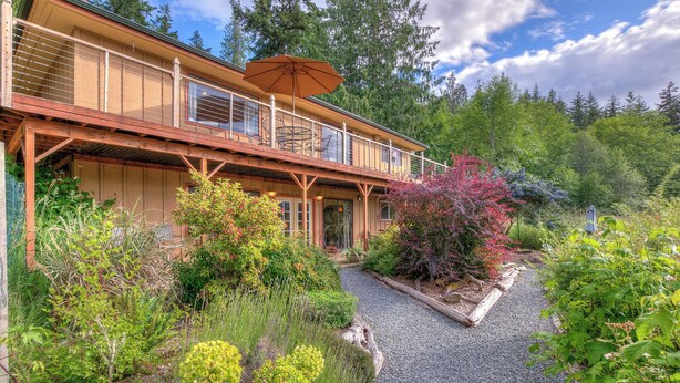 A wooden building with a balcony and a gravel path leading to the entrance. - AUTUMN SALE! Cedar Field House on 2 Acres - horseshoes, Volleyball, Fire pit (Eastsound)