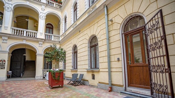 A courtyard with a tiled floor, a wooden door, and a wrought iron gate. - Boutique flat in Akacfa street (Budapest)