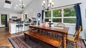 Een ruime keuken met een eethoek, met een grote houten tafel, barstoelen en een kroonluchter.
