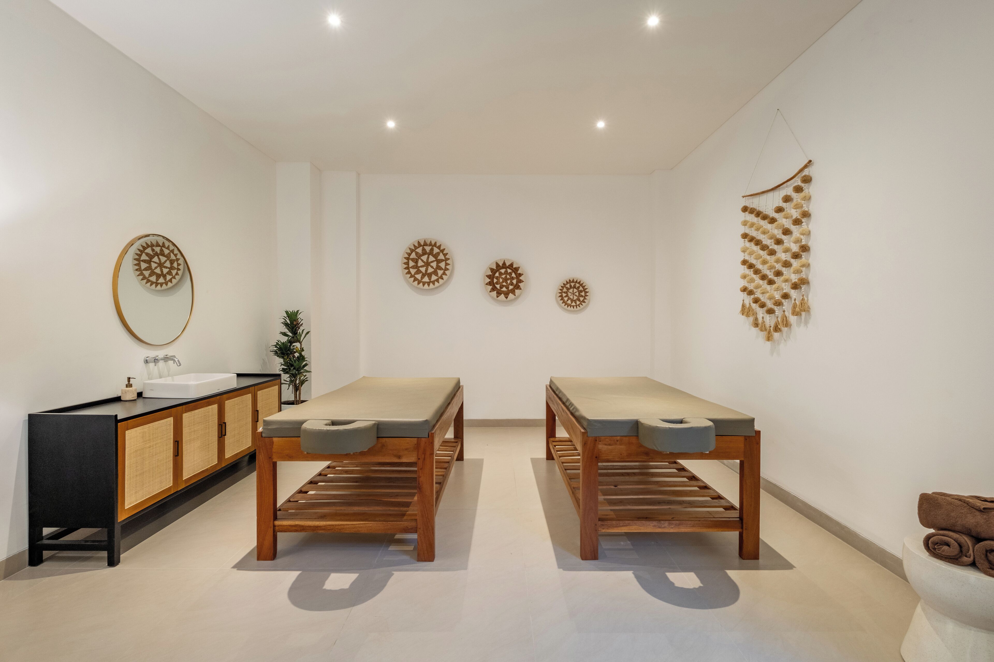 Une salle de bain moderne avec deux bancs en bois, un meuble noir avec un lavabo et des éléments décoratifs muraux.