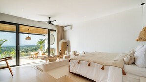 Ein Schlafzimmer mit einem großen Bett, einem Deckenventilator und Blick ins Freie.
