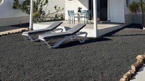 Un bâtiment moderne doté d’un espace extérieur aménagé et abrité, comprenant des fauteuils et une table.