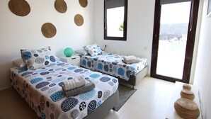 Une chambre avec deux lits, une grande fenêtre et une vue sur l’extérieur.