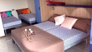 Um quarto com duas camas de solteiro, um sofá-cama e uma cama beliche.