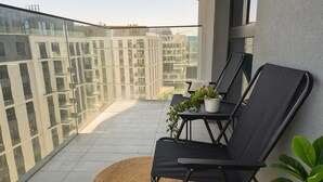 A balcony with two black lounge chairs, a small table with a potted plant, and a view of modern buildings. - Boutique Hotel Echo Residence (Belgrade)