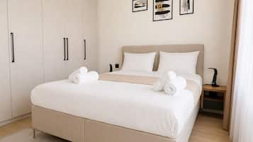 Un dormitorio moderno con una cama grande, un armario y una mesita de noche con una lámpara.