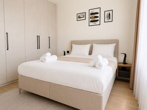 Une chambre moderne avec un grand lit, une armoire et une table de chevet avec une lampe.