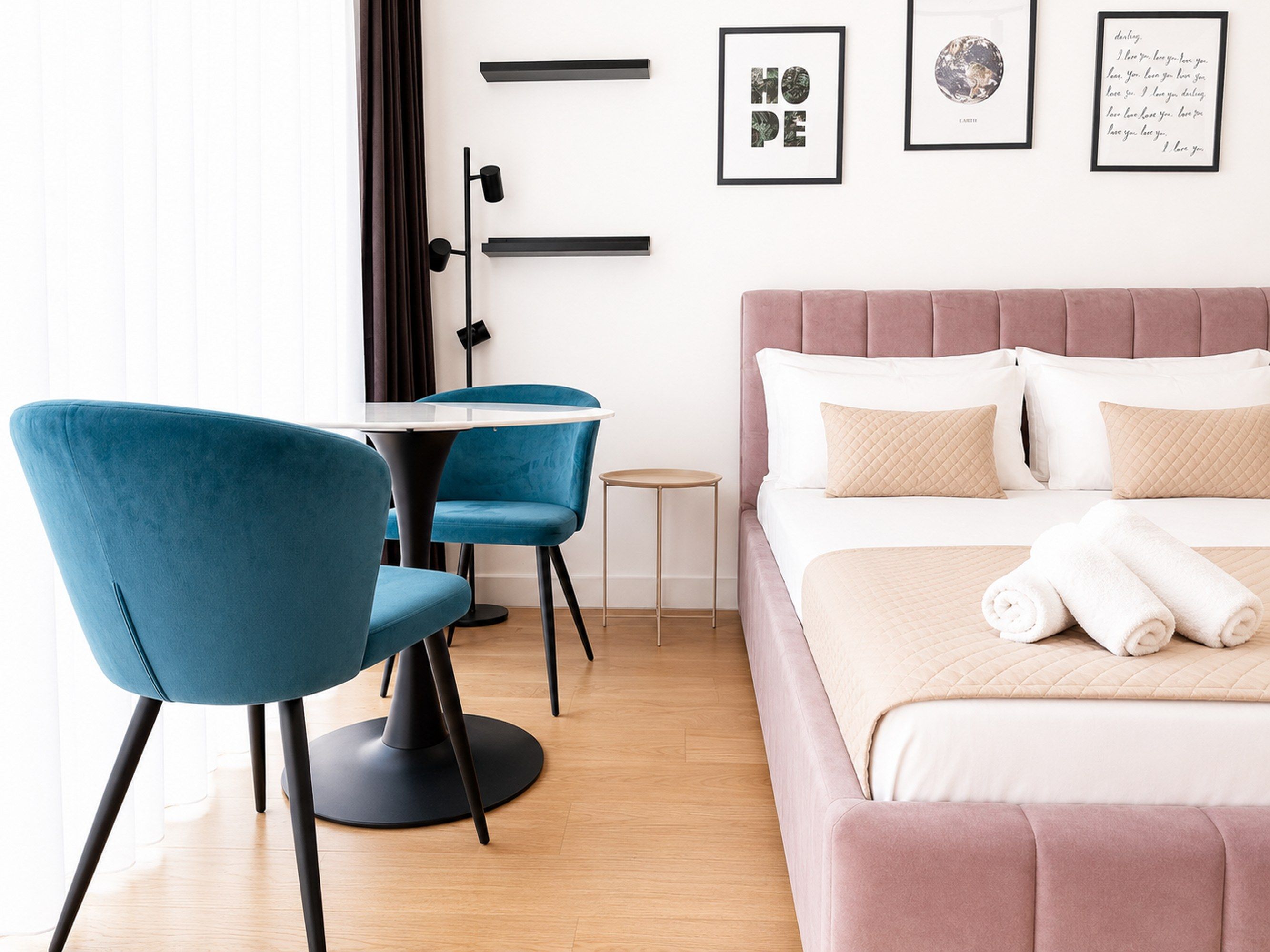 Una habitación de hotel moderna con una cama, un escritorio, dos sillas y una mesita.