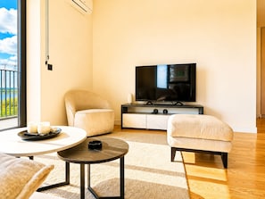 A modern living room with a flat-screen TV, two armchairs, a coffee table, and a view of the outdoors. - Boutique Hotel Echo Residence (Belgrade)