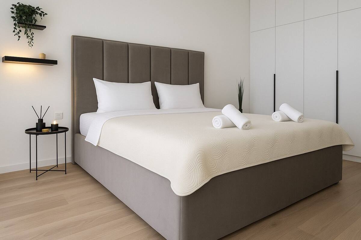 Un dormitorio moderno con una cama grande, una mesita de noche con velas y un estante de pared con una planta.