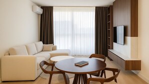 A modern living room with a sofa, a round table, and a flat-screen TV mounted on the wall. - Boutique Hotel Echo Residence (Belgrade)