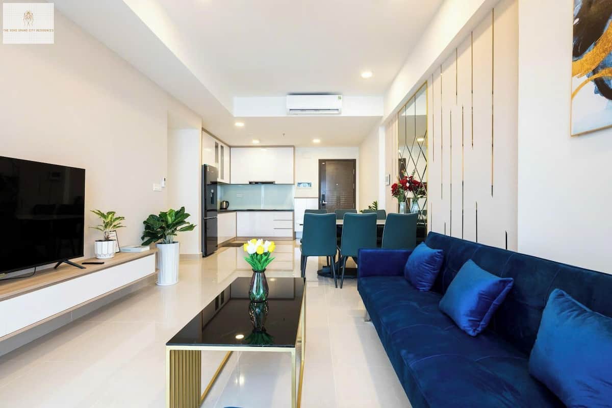 A modern living room with a flat-screen TV, a sofa, a coffee table, and a vase of flowers.