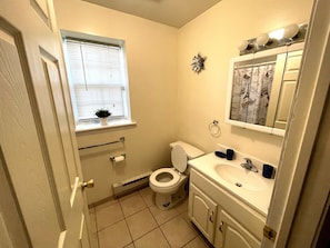 A small bathroom with a toilet, sink, and window.