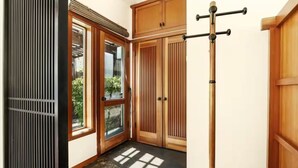 Um canto de um quarto com portas de madeira, uma porta de vidro deslizante e um mastro vertical com barra horizontal.