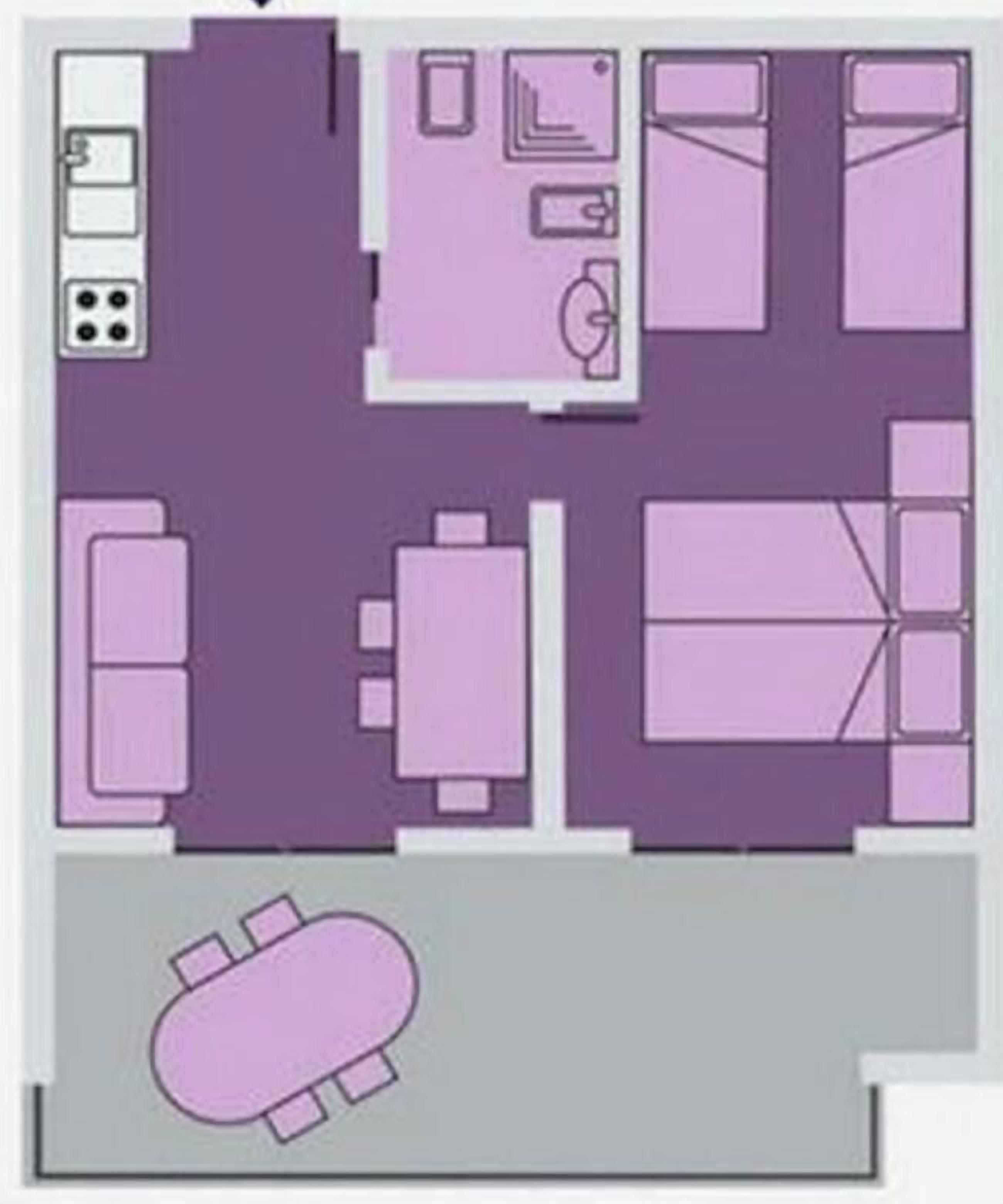 A hotel room layout with a bed, seating area, and a small kitchenette.