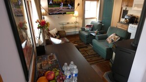 Een woonkamer met een televisie, bank en een tafel met fruit en waterflessen.