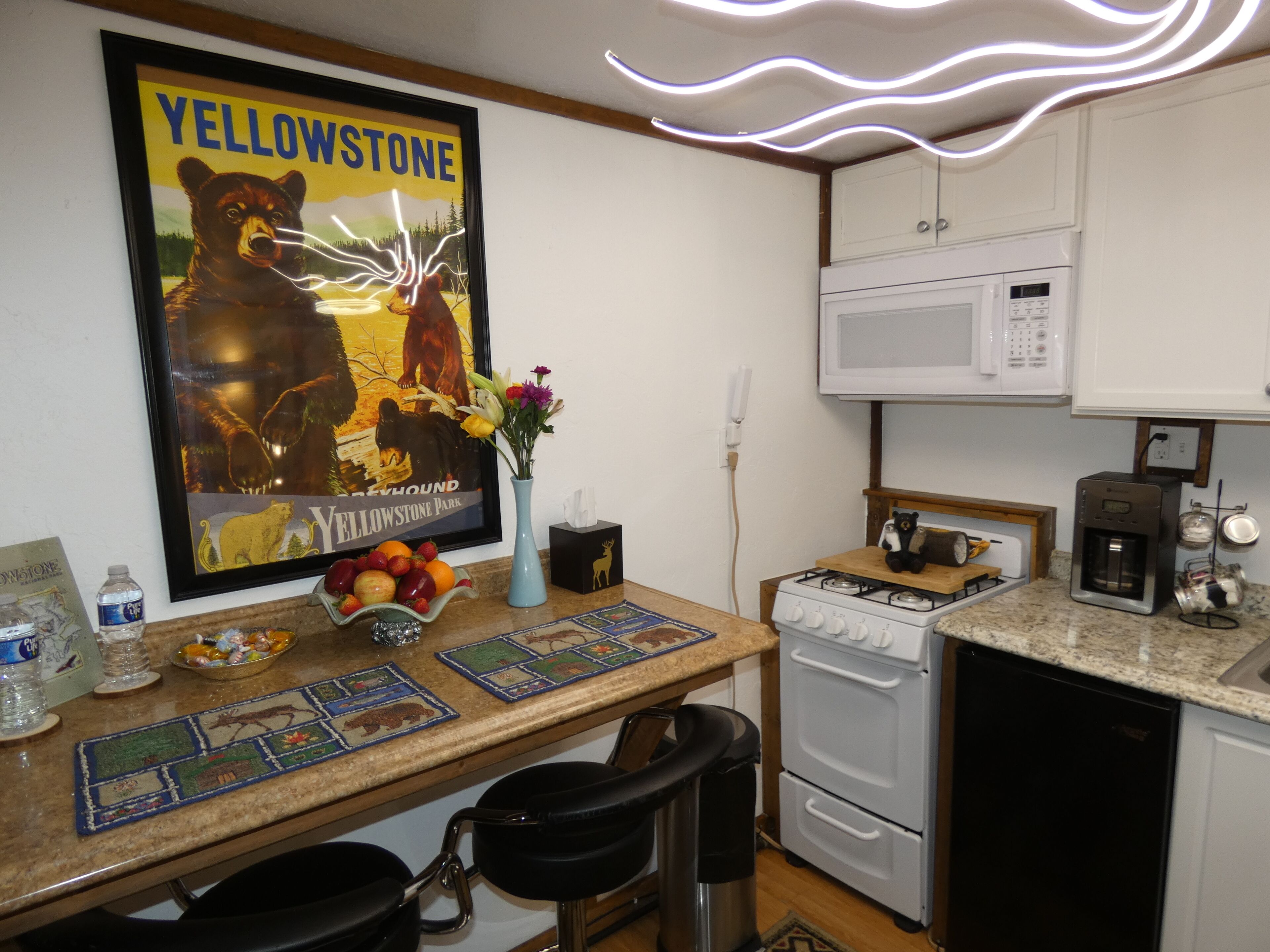 A kitchen with a bear poster, a microwave, a stove, and a sink.