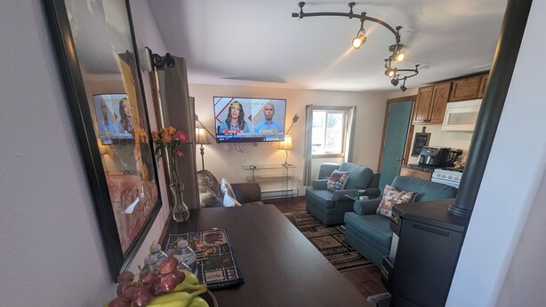 Een moderne woonkamer met een donker houten salontafel, een blauwe bank en een keuken met een fornuis en magnetron.