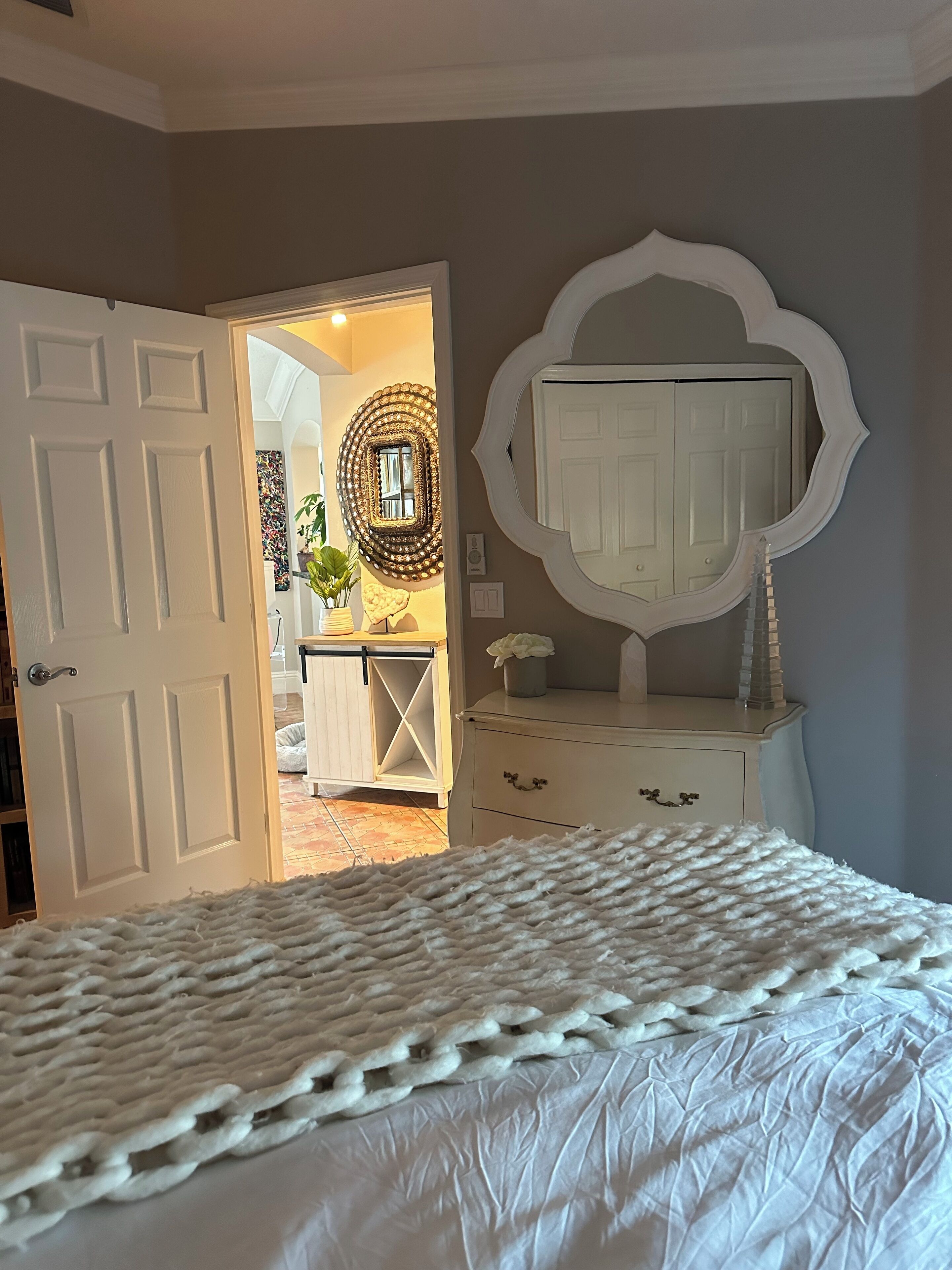 Une chambre à coucher avec un lit, une commode et un miroir au mur.