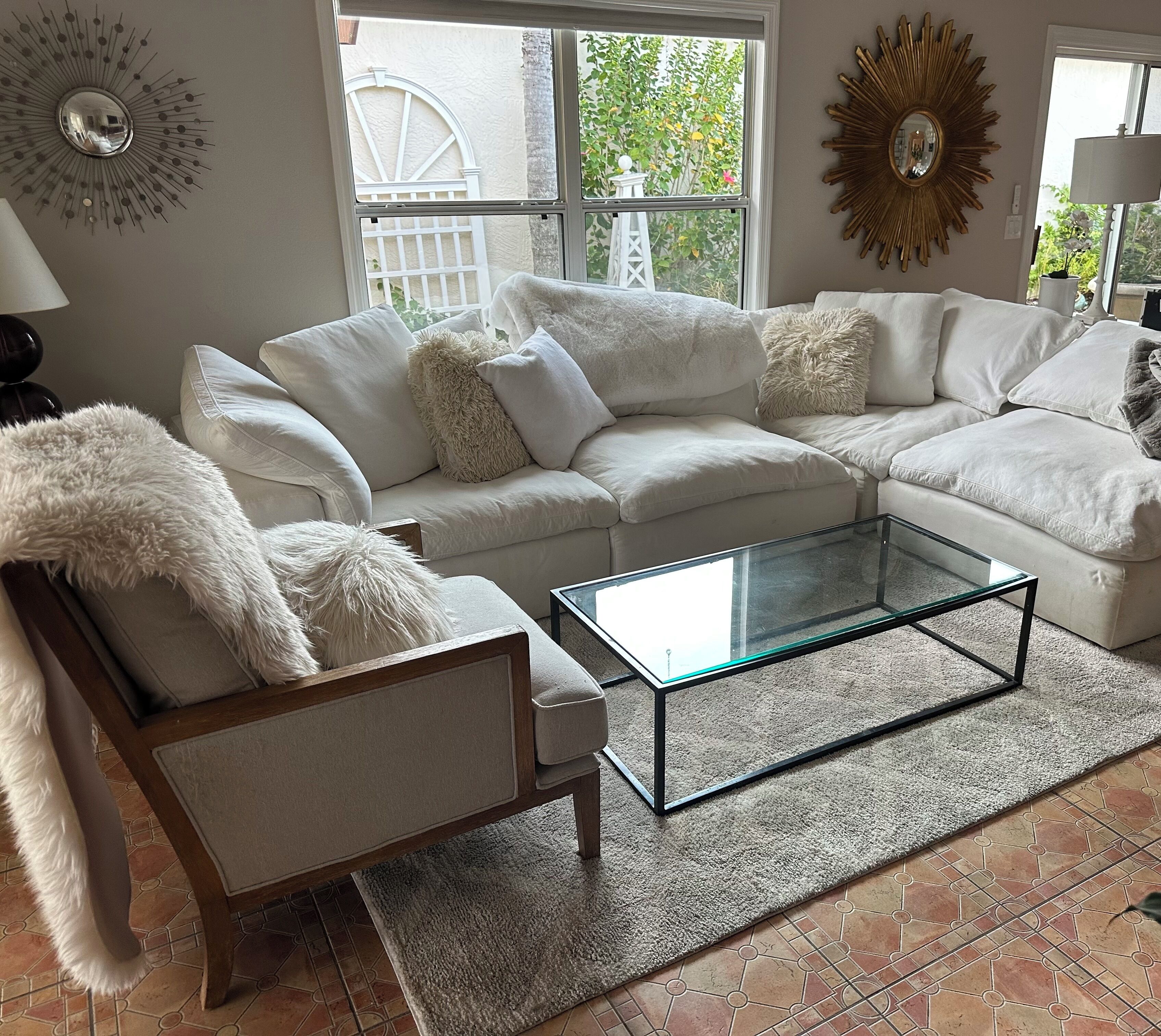 A living room with a sectional sofa, a glass coffee table, and a fluffy chair.