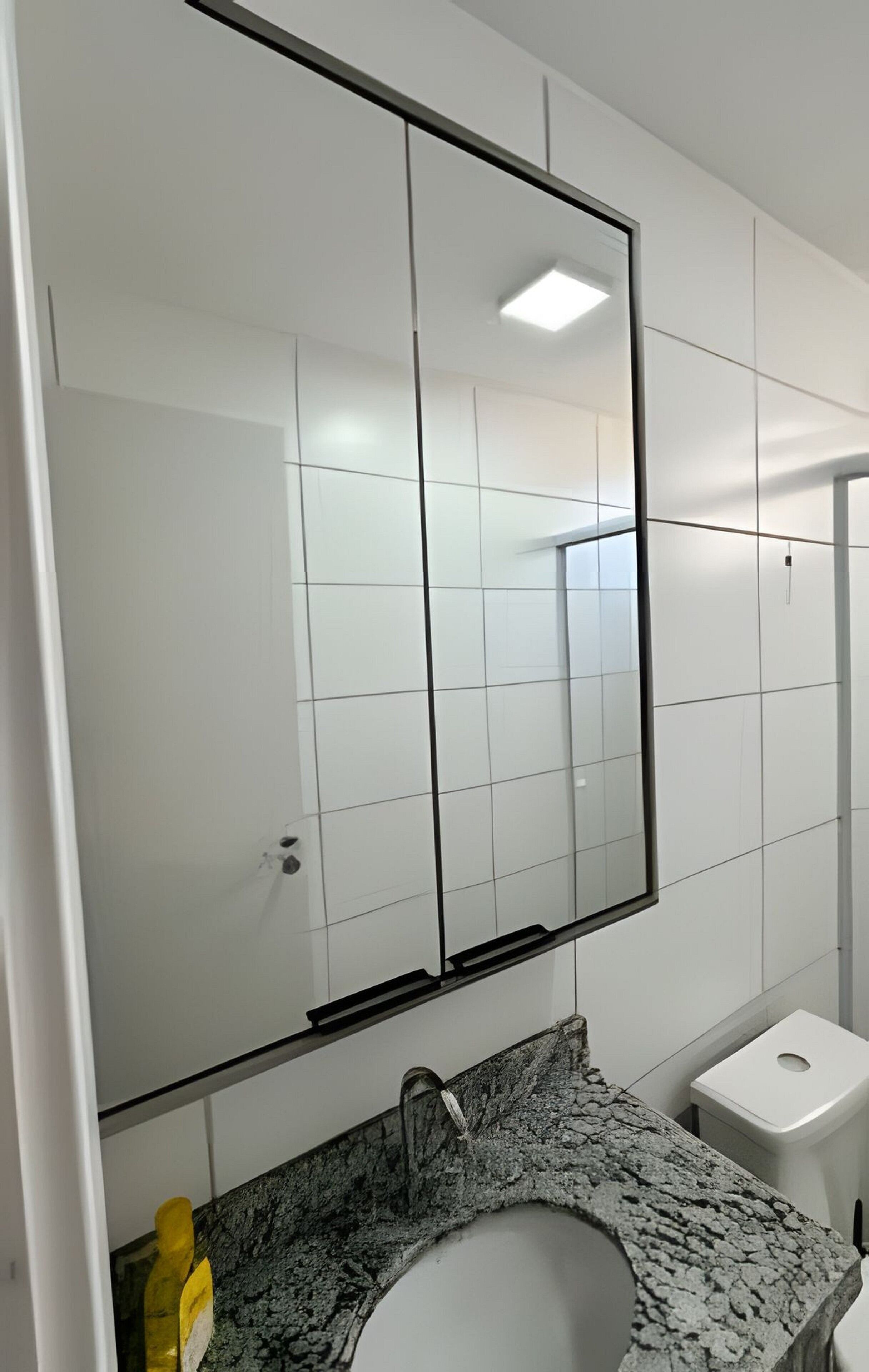 A bathroom with a white sink, a mirror, and a toilet.