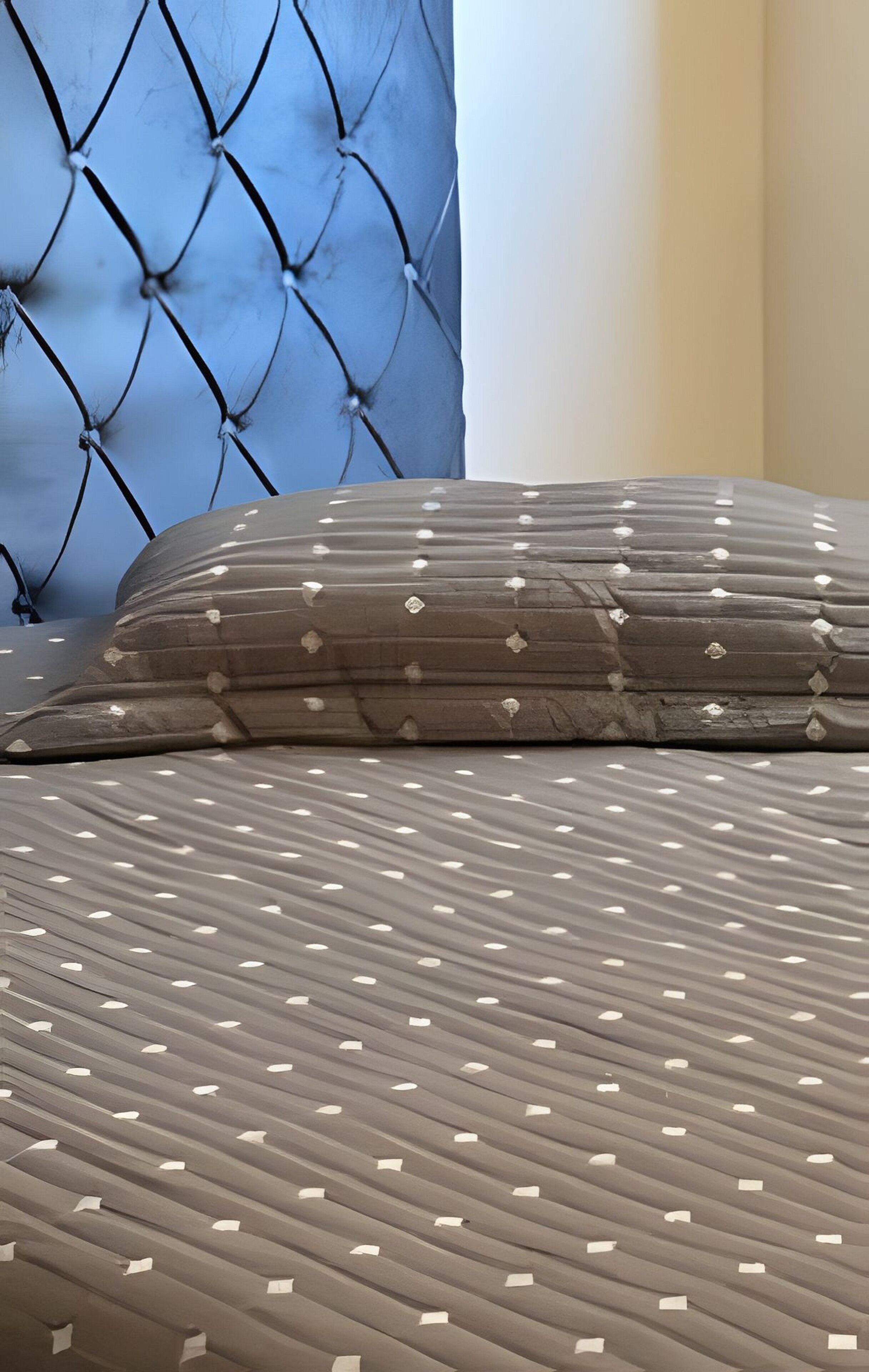 A bed with a patterned bedspread and a tufted headboard.