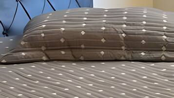 A bed with a patterned bedspread and a tufted headboard.