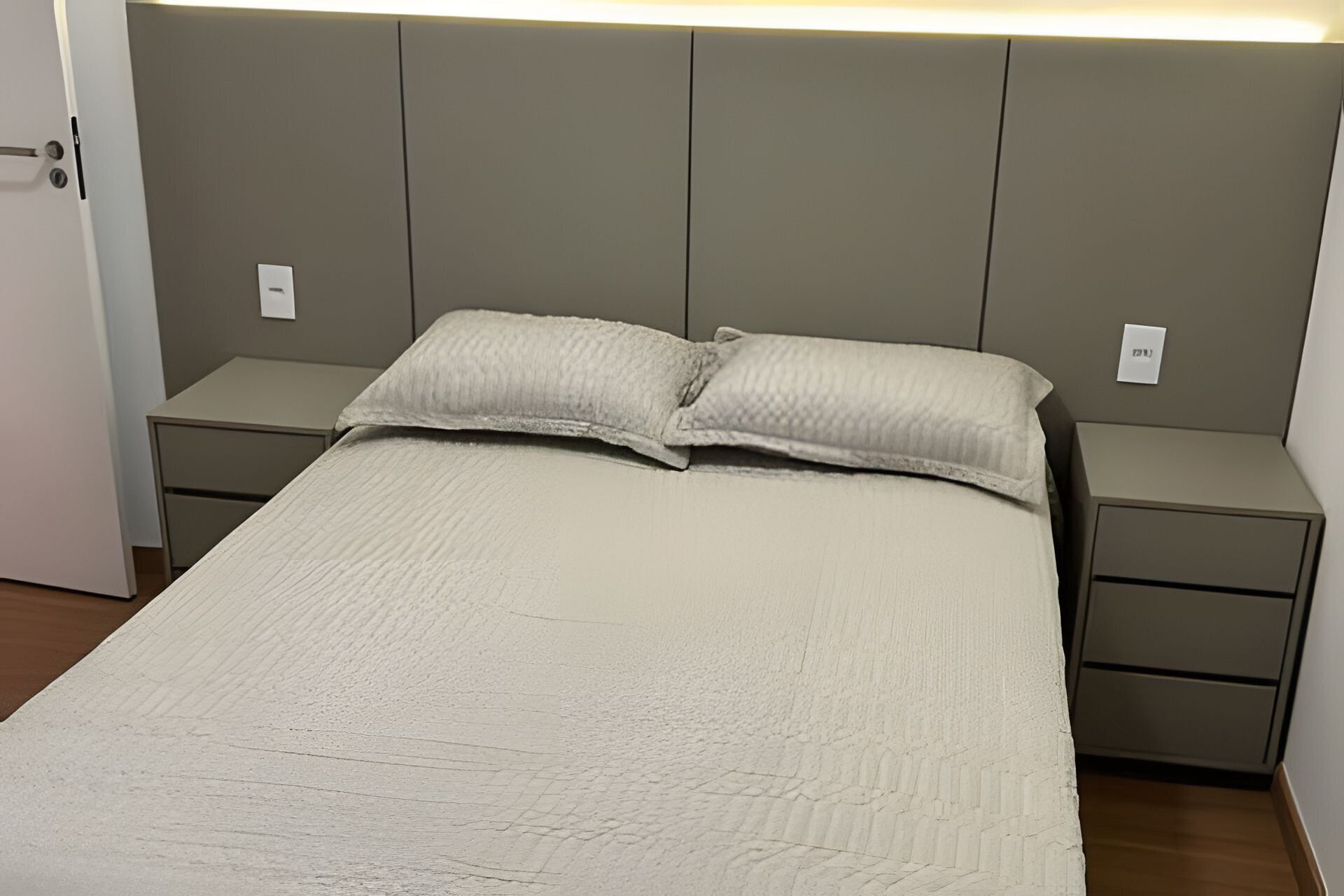 Un dormitorio con una cama, dos mesitas de noche y una puerta.