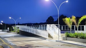 A modern bridge with metal railings and a staircase leading to a building. Street lamps are visible, and the sky is clear. - Mel Prime Executive Loft Extrema MG (Extrema)