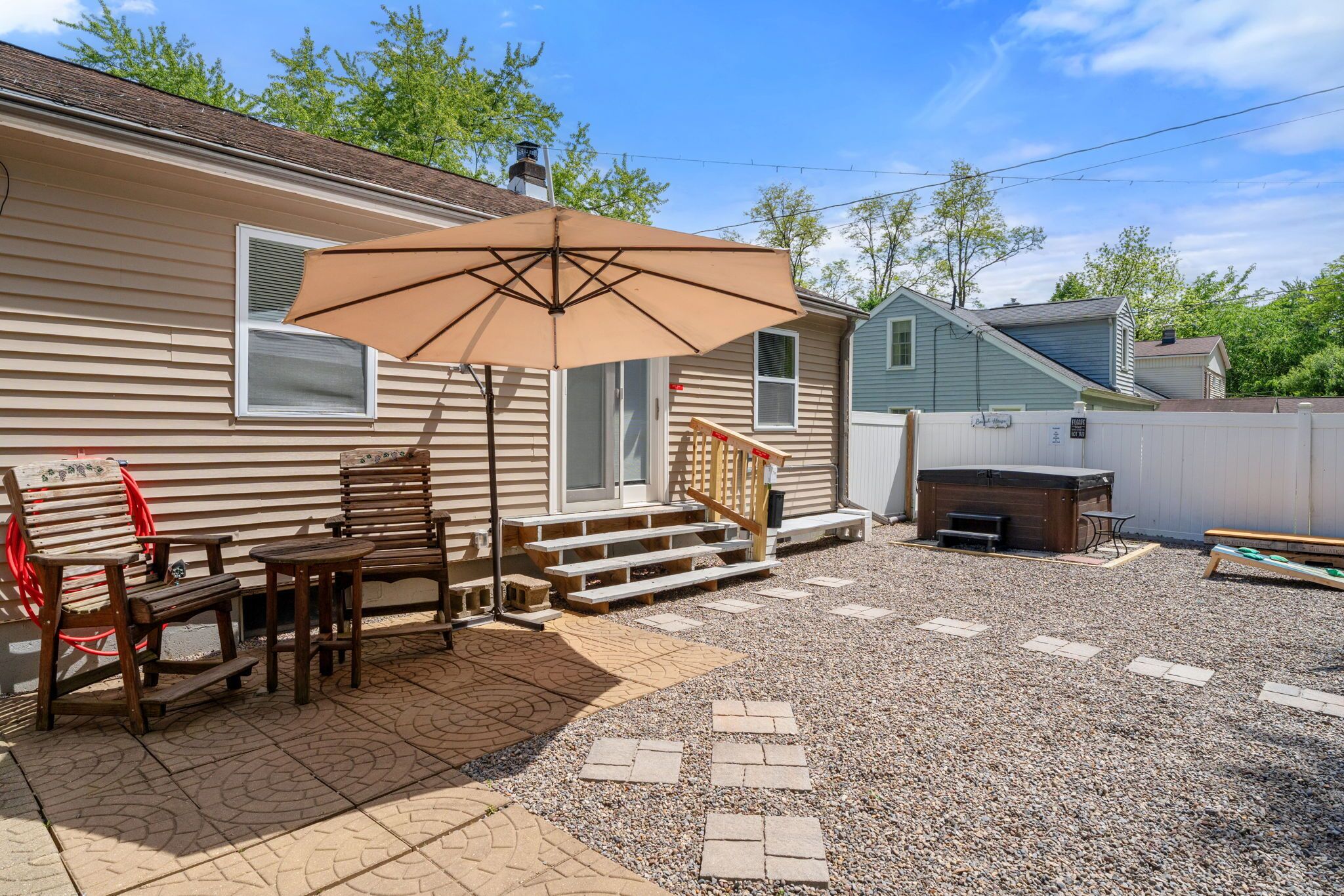 A backyard with a patio, wooden furniture, a barbecue grill, and a covered seating area.