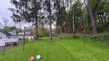 A fenced outdoor area with a volleyball net, two volleyballs, and a red banner.