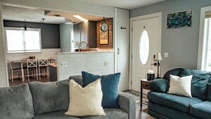Ein Wohnzimmer mit einem grauen Sofa, einem grünen Sofa und einem Essbereich mit Tisch und Stühlen.