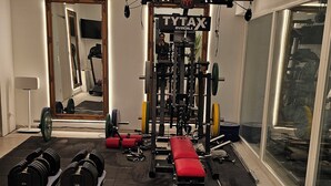 Une salle de sport équipée de matériel de musculation, dotée d’un miroir et d’une grande fenêtre.
