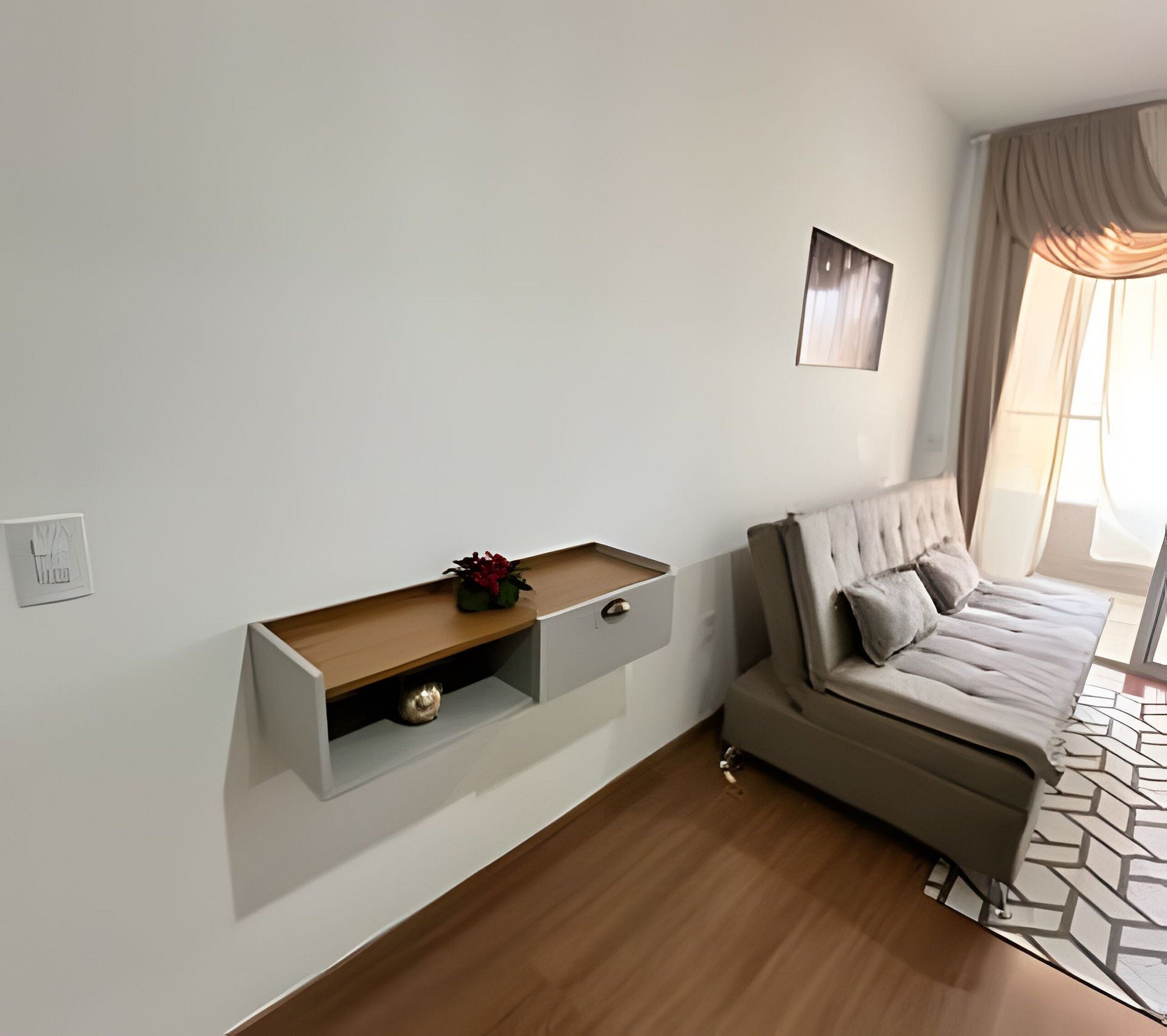 Ein modernes Wohnzimmer mit einer Couch, einer eingebauten Vitrine mit Dekoration und einem Fenster mit Vorhängen.