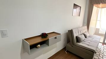 Ein modernes Wohnzimmer mit einer Couch, einer eingebauten Vitrine mit Dekoration und einem Fenster mit Vorhängen.