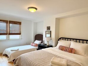 A hotel room with two beds, a nightstand, a lamp, and a ceiling light. - Boston Single House 2BR - Backyard + Walk to BCEC & Seaport (Boston)