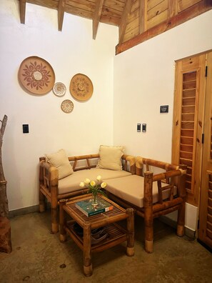 A cozy room with a wooden sofa, a coffee table with a book and flowers, and decorative plates on the wall. - Cozy 2-bedroom cabin where nightfall reveals its most magical scenery (Cabrera)