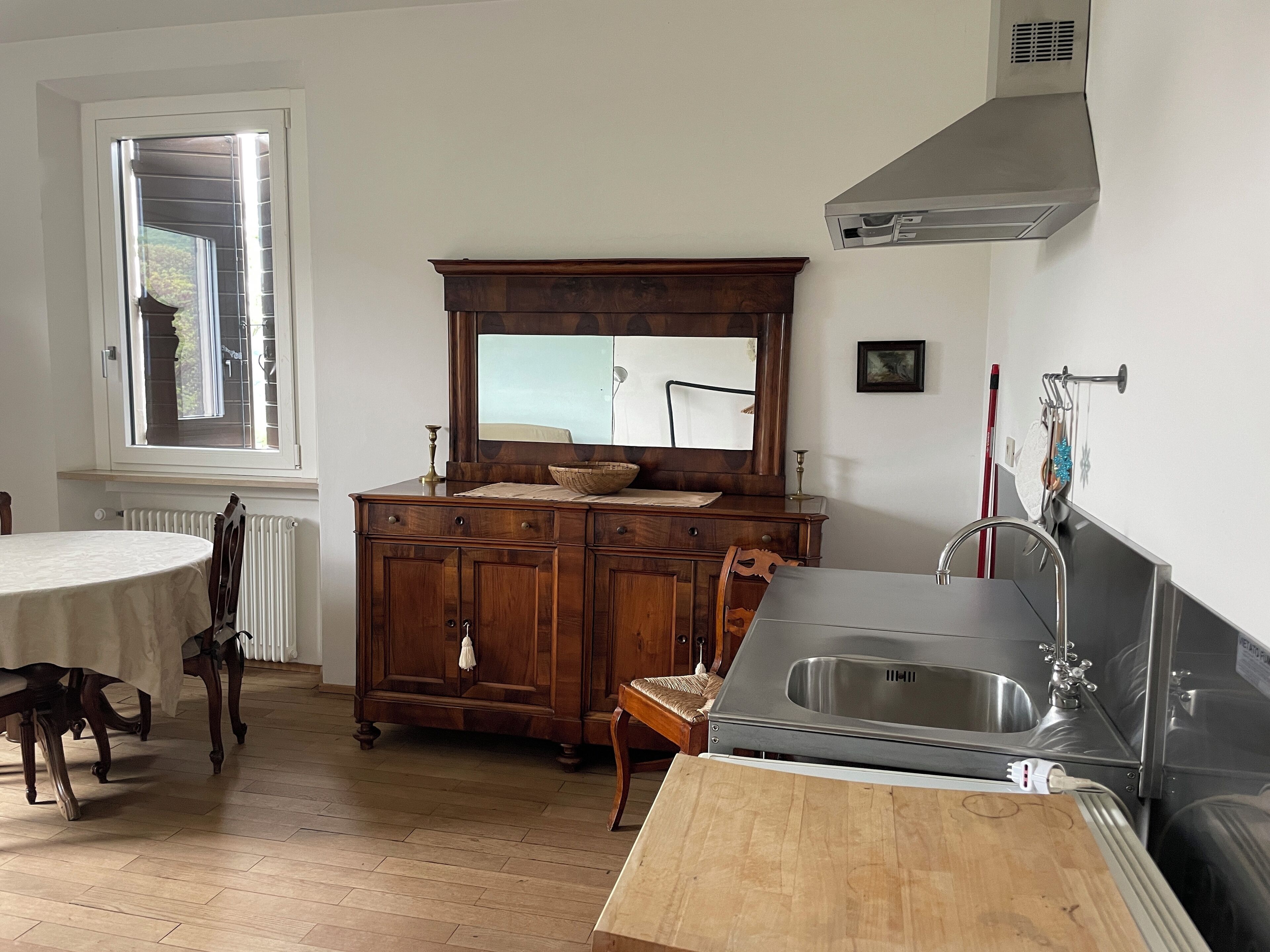 Una cucina con un mobiletto in legno, un lavello e una finestra.