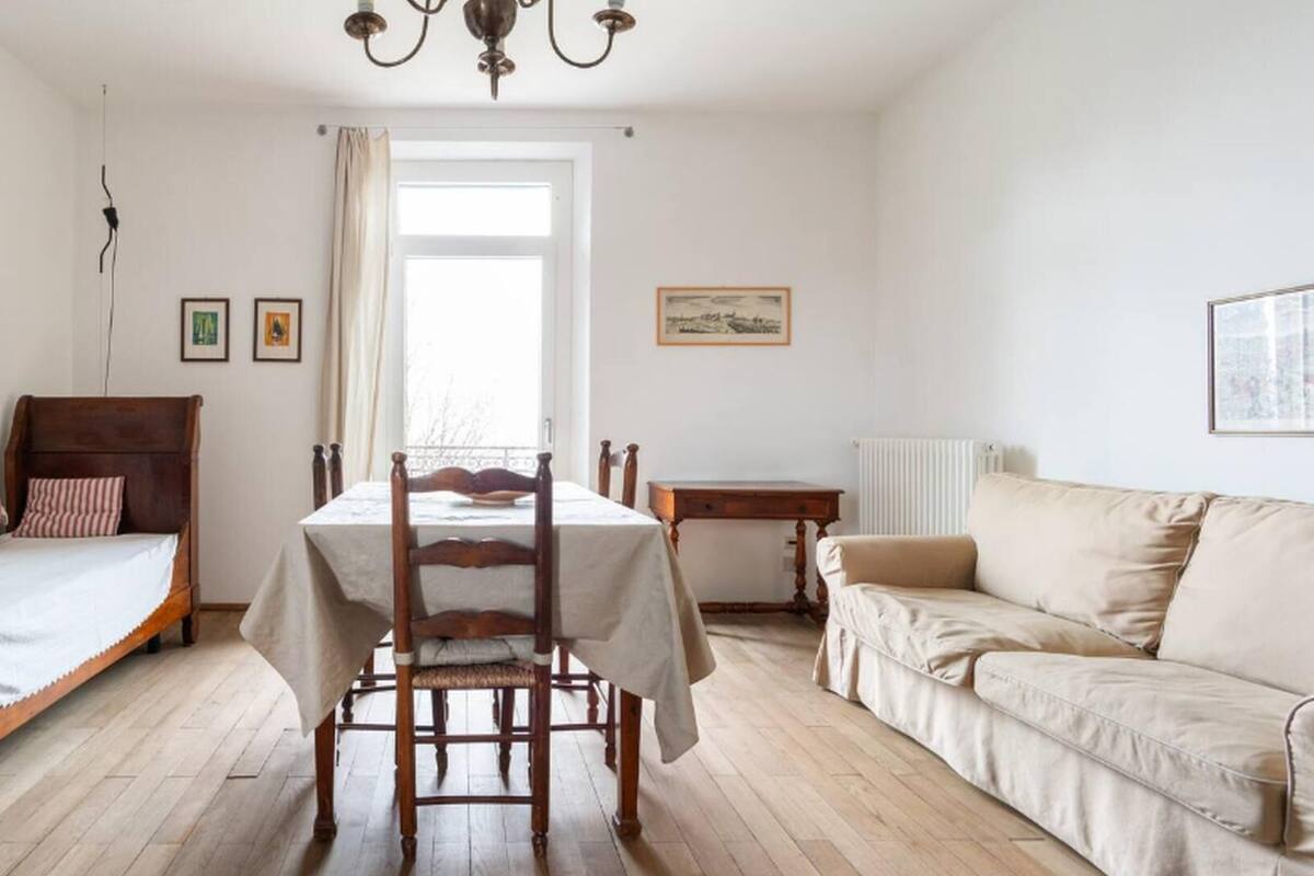 A bedroom with a wooden bed, a dining table, and a sofa.