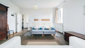 Un dormitorio con una cama, un armario de madera, una silla y una lámpara colgante.