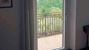 Una habitación con un gran ventanal corredero que da a un balcón con barandilla de metal.