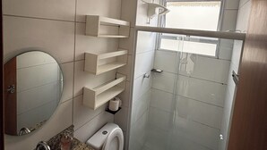 Baño con lavamanos, inodoro y cabina de ducha de vidrio.