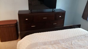 Une chambre à coucher avec un lit, une commode et un téléviseur posé sur le dessus.