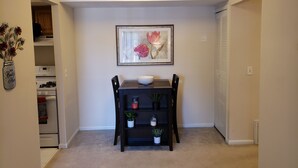 Un coin repas avec une table, des chaises, un bol et un tableau encadré accroché au mur.