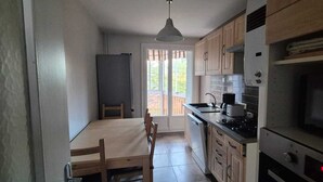 Una cucina compatta con mobili in legno, un tavolo da pranzo e un forno integrato.