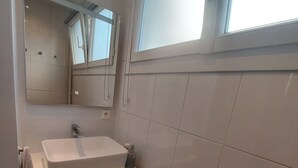Un bagno moderno con lavandino, specchio e finestra bianchi.