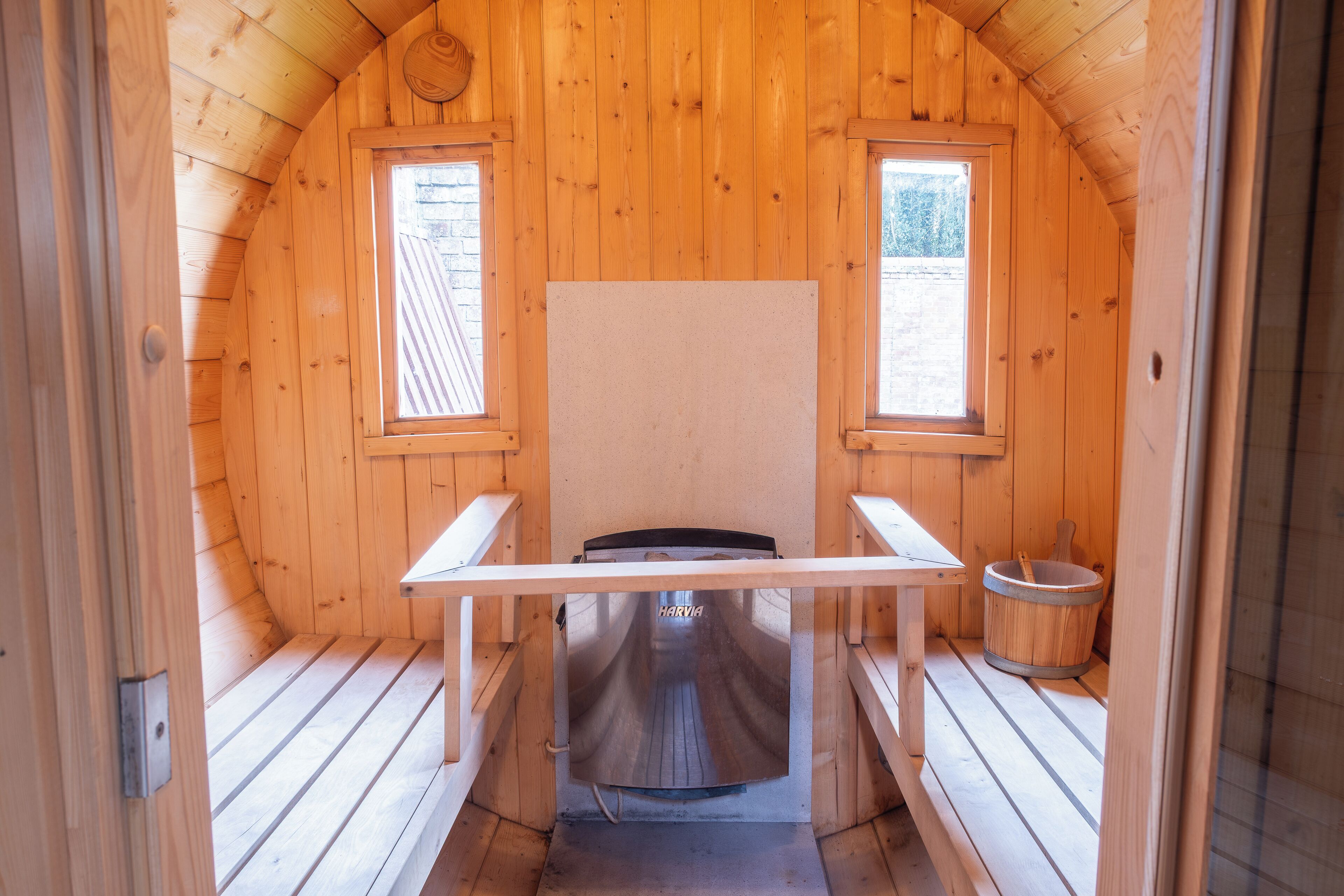 A wooden cabin with a sauna, two windows, and a wooden bench.