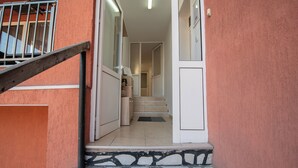 Eine Treppe führt zu einem Raum mit Fliesenboden und einer Tür, vor der eine kleine Fußmatte liegt.