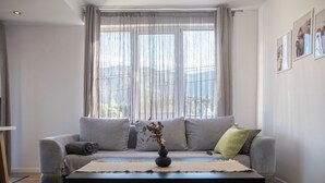 Ein modernes Wohnzimmer mit einem grauen Sofa, einem schwarzen Couchtisch und einem Blumenstrauß.